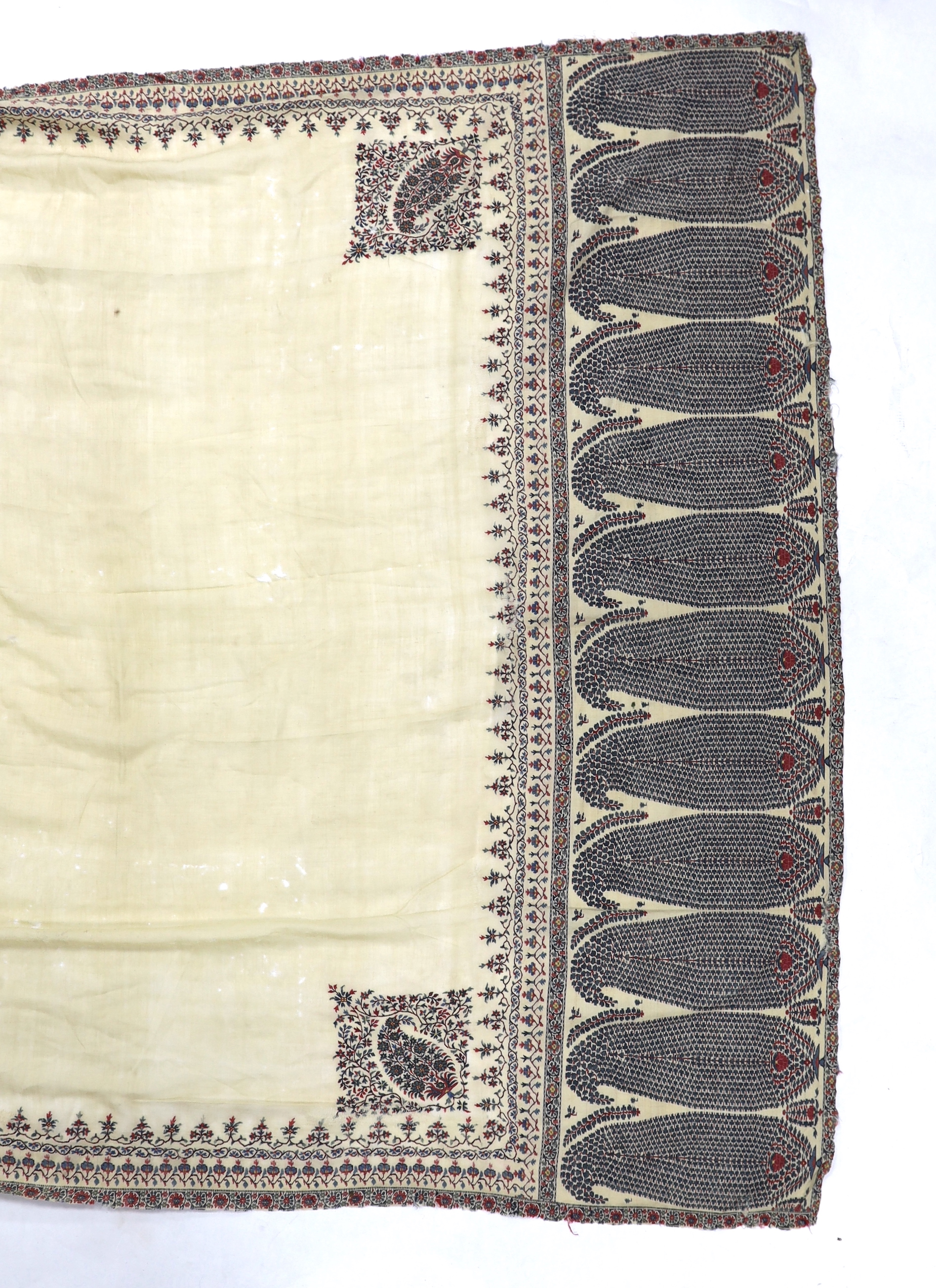 A 19th century fine cream woven Kashmiri shawl with blue and red teardrop design borders, an early 20th century gold satin pelmet with spot motifs of peacocks and flowers, 204cm long x 71cm high and a length of silk with